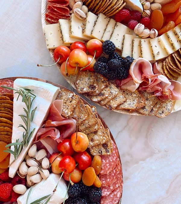 two round charcuterie boards with cherries, blackberries, cheese, meats, and nuts